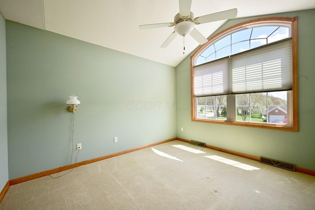 carpeted empty room featuring visible vents, a ceiling fan, vaulted ceiling, and baseboards