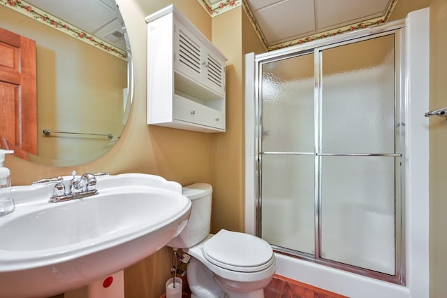 bathroom featuring toilet, a sink, a shower stall, and wood finished floors