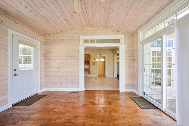 interior space featuring wood walls, baseboards, wooden ceiling, vaulted ceiling, and a notable chandelier