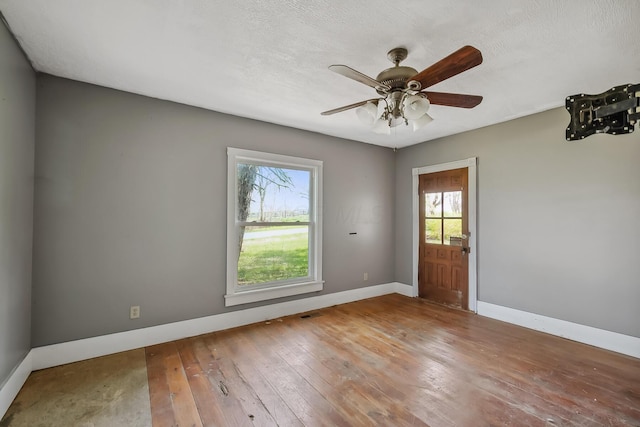 spare room featuring hardwood / wood-style floors, ceiling fan, and baseboards