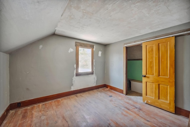 additional living space with hardwood / wood-style floors, vaulted ceiling, and baseboards
