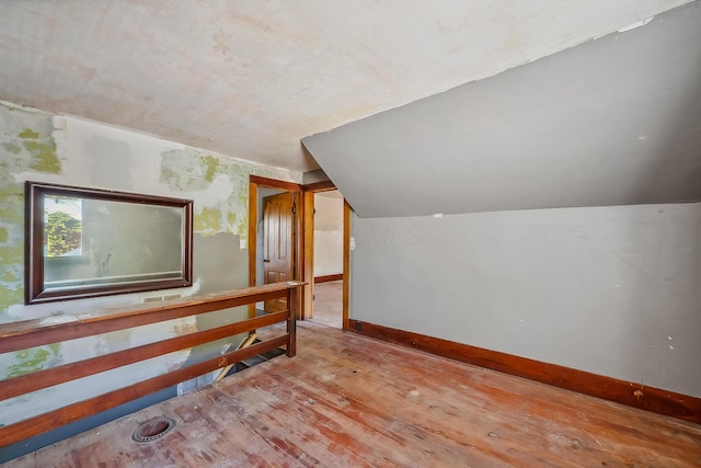 bonus room featuring lofted ceiling, hardwood / wood-style flooring, and baseboards
