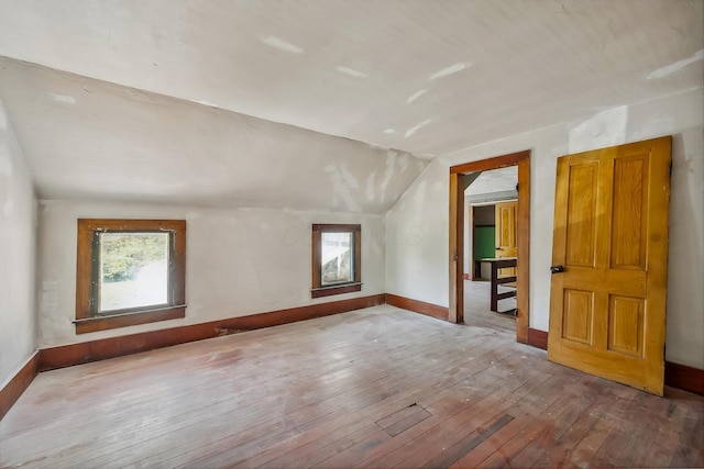 bonus room with wood-type flooring, lofted ceiling, and baseboards