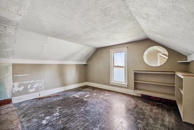 bonus room featuring a textured ceiling, hardwood / wood-style floors, lofted ceiling, and baseboards