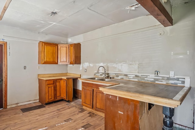 kitchen with light wood-style floors, light countertops, brown cabinetry, and a sink