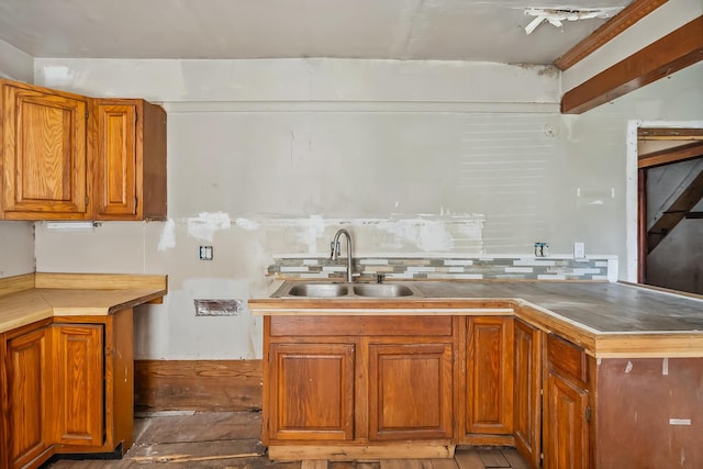 kitchen featuring hardwood / wood-style floors, brown cabinetry, backsplash, and a sink