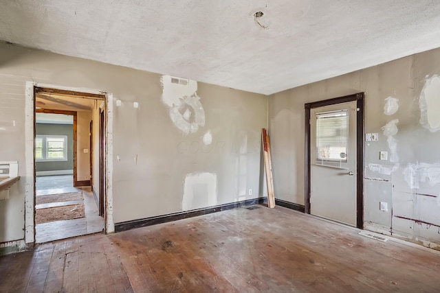 unfurnished room featuring baseboards, visible vents, and hardwood / wood-style flooring