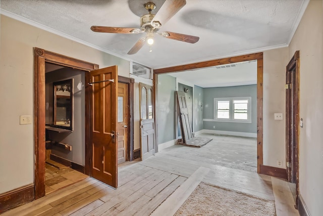interior space with ornamental molding, light wood finished floors, baseboards, visible vents, and a ceiling fan