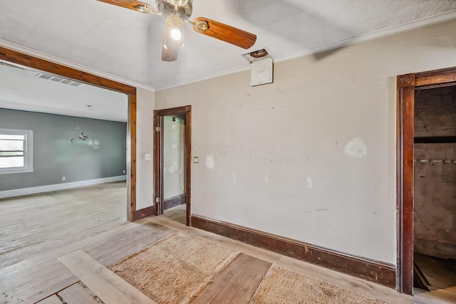 unfurnished room featuring visible vents, hardwood / wood-style floors, baseboards, ornamental molding, and a ceiling fan