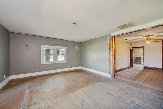 unfurnished room featuring visible vents, ceiling fan, hardwood / wood-style floors, and baseboards