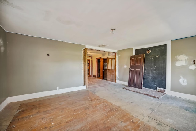 empty room featuring baseboards, visible vents, and wood finished floors