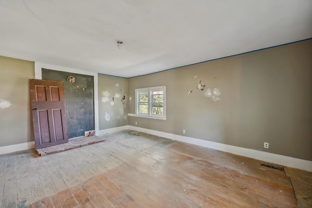 unfurnished living room with baseboards and wood finished floors