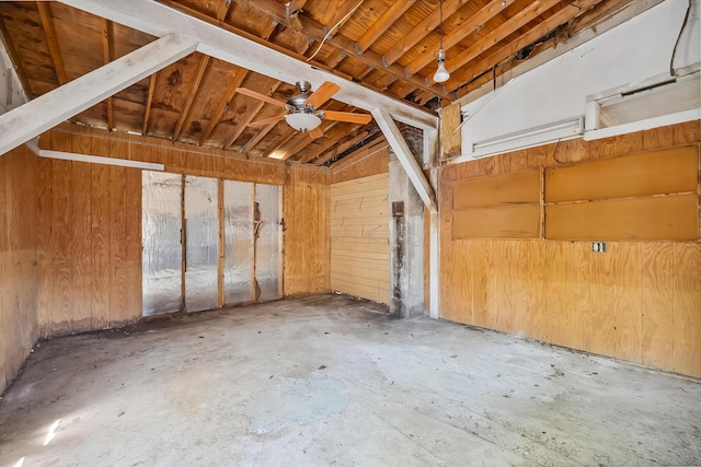 interior space featuring ceiling fan and wood walls