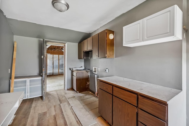 kitchen with white cabinets, light wood finished floors, and vaulted ceiling