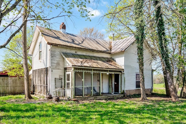 back of house featuring fence, a chimney, and a lawn