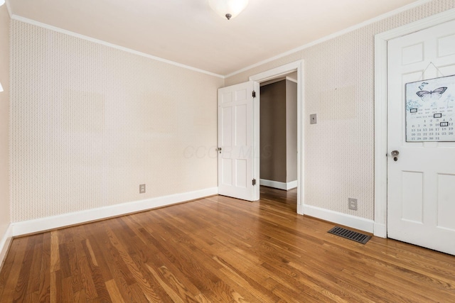 unfurnished room with crown molding, baseboards, visible vents, and wood finished floors