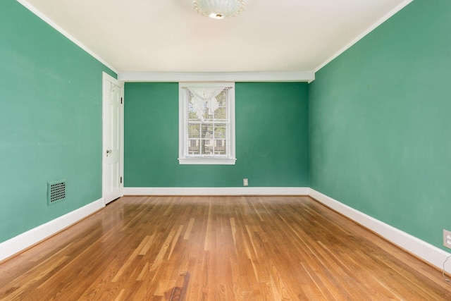 empty room with visible vents, baseboards, crown molding, and wood finished floors
