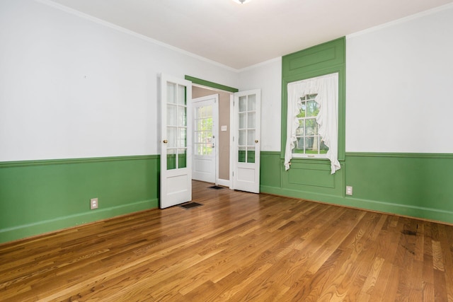 spare room with plenty of natural light, ornamental molding, wood finished floors, and french doors