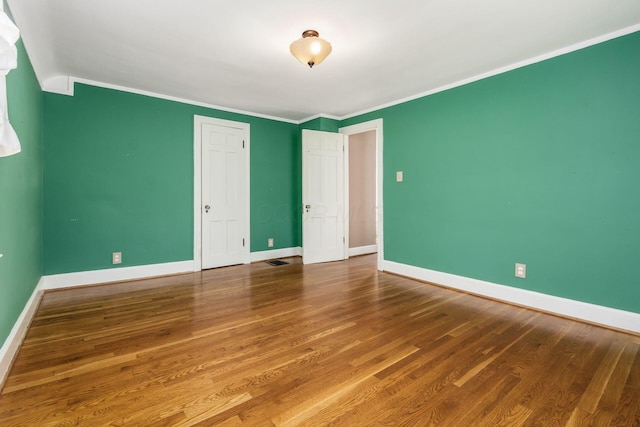 unfurnished bedroom featuring baseboards, visible vents, ornamental molding, and wood finished floors