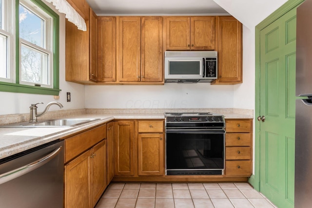 kitchen with a sink, appliances with stainless steel finishes, brown cabinets, and light countertops