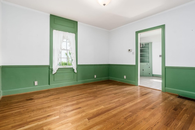 unfurnished room with baseboards, ornamental molding, and wood finished floors