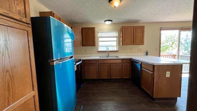 kitchen with freestanding refrigerator, a peninsula, dishwashing machine, a textured ceiling, and a sink