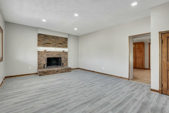 3907 Condit Rd, Sunbury, OH 43074 - unfurnished living room with wood finished floors, a textured ceiling, a fireplace, baseboards, and recessed lighting