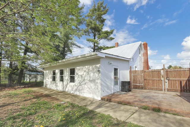 3907 Condit Rd, Sunbury, OH 43074 - view of side of home featuring a gate, a chimney, fence, a patio, and metal roof