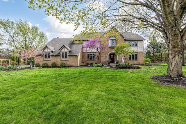 tudor house featuring a front yard and brick siding
