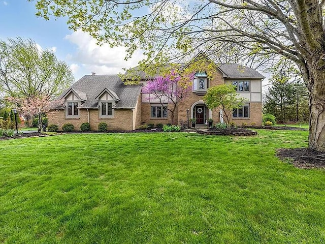 tudor home with a front yard and brick siding