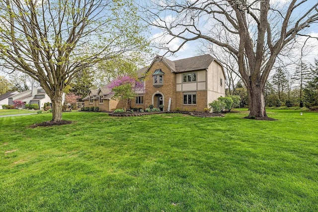 tudor-style house with brick siding and a front yard