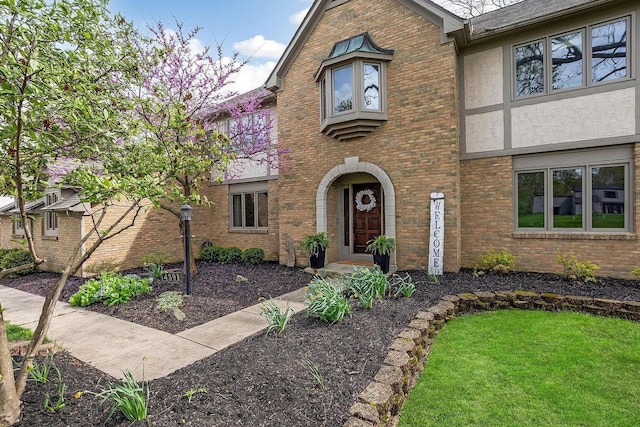 view of front of house with stucco siding, brick siding, and a front lawn