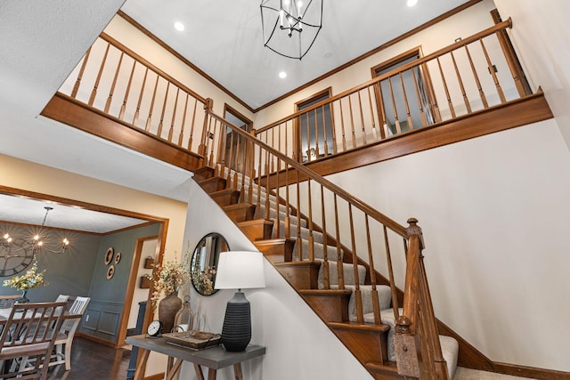 stairs featuring a chandelier, crown molding, recessed lighting, baseboards, and a high ceiling
