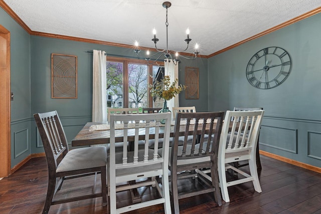 dining room with a decorative wall, a chandelier, dark wood finished floors, a textured ceiling, and ornamental molding