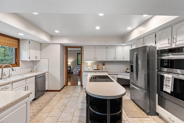 kitchen with appliances with stainless steel finishes, a sink, light countertops, decorative backsplash, and recessed lighting