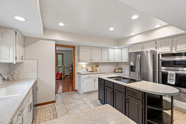 kitchen with appliances with stainless steel finishes, a sink, white cabinets, baseboards, and light countertops