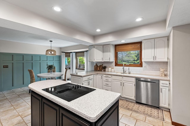 kitchen featuring stainless steel dishwasher, black electric stovetop, tasteful backsplash, a sink, and white cabinetry