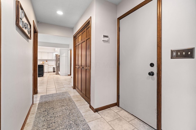 corridor featuring baseboards, light tile patterned floors, and recessed lighting
