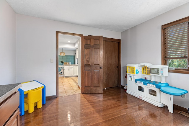 game room featuring wood finished floors, baseboards, and a textured ceiling
