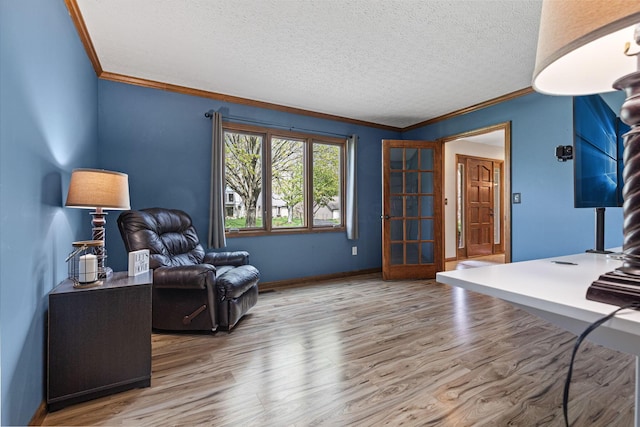 living area featuring crown molding, wood finished floors, a textured ceiling, and baseboards