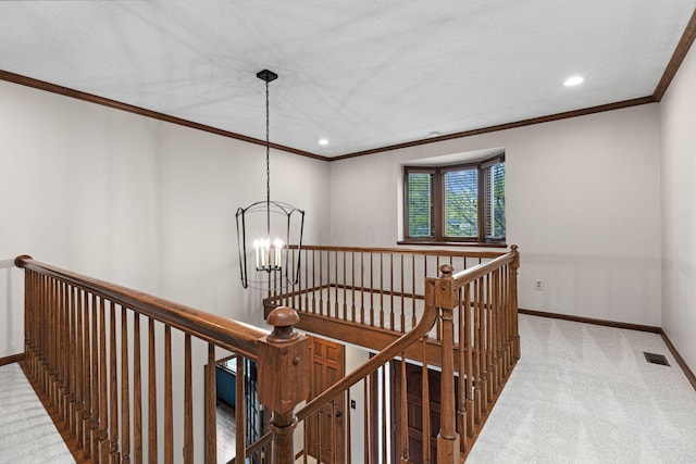 hallway with an upstairs landing, a chandelier, carpet, ornamental molding, and baseboards