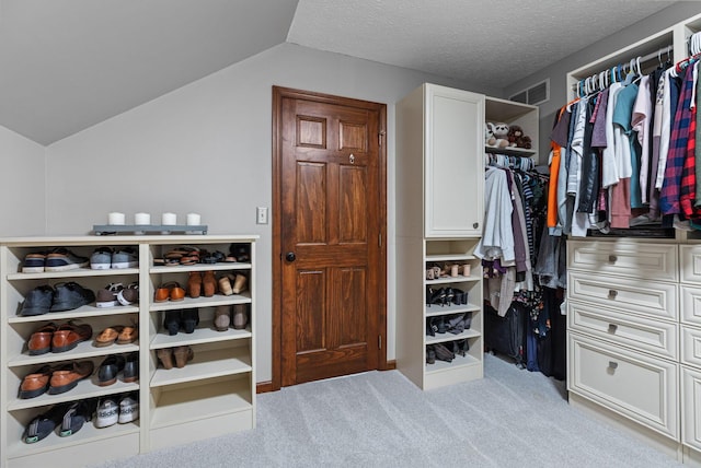 walk in closet featuring light carpet and vaulted ceiling