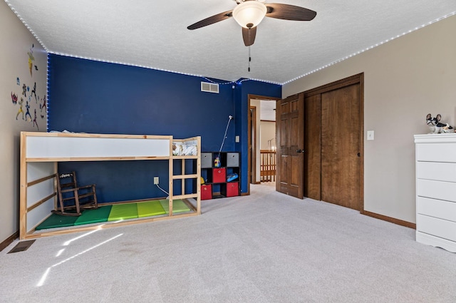 carpeted bedroom with a textured ceiling, a closet, baseboards, and ceiling fan