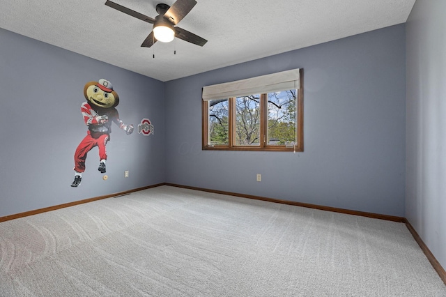 carpeted spare room with ceiling fan, a textured ceiling, and baseboards