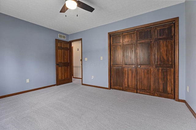 unfurnished bedroom featuring light carpet, baseboards, a textured ceiling, and a ceiling fan