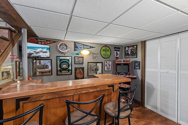 indoor dry bar with a paneled ceiling and dark wood-style flooring