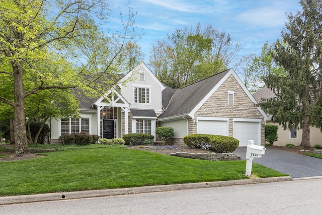 view of front of house with roof with shingles, aphalt driveway, a front lawn, and stone siding