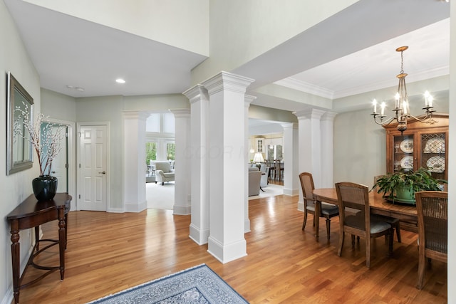 dining room featuring ornamental molding, baseboards, ornate columns, light wood finished floors, and a notable chandelier