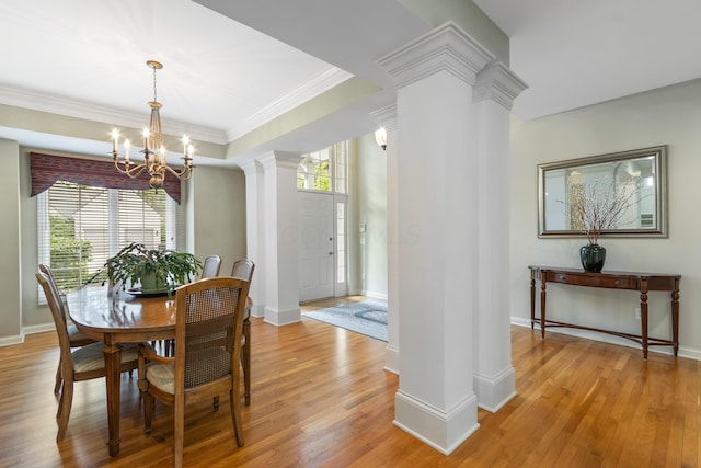dining room with light wood-style floors, decorative columns, crown molding, and a notable chandelier