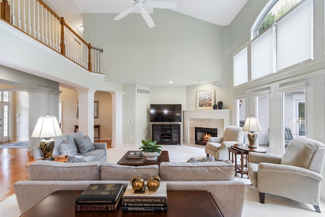 living room with visible vents, decorative columns, a fireplace, ceiling fan, and high vaulted ceiling